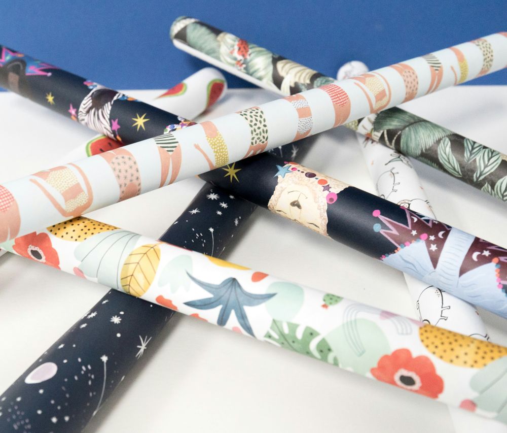 Assorted IndianWrap wrapping paper rolls in playful designs crossed on a table